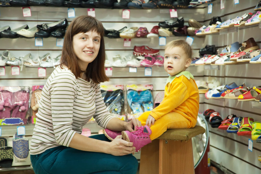 Photo of woman with child chooses baby shoes